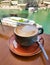 Dark blue cup of cappuccino on table overlooking the river, yachts and boats. Morning breakfast.