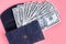 Dark blue leather wallet with money on pink background composition