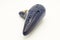 A dark blue ocarina in front of white background