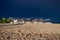 The dark blue sky is above the beach bar by the sea. It`s like a storm. The beach is empty and there are no people