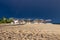 The dark blue sky is above the beach bar by the sea. It`s like a storm. The beach is empty and there are no people