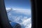 Dark Blue Sky and Clouds and an Airplane Wing and Engine Seen Through an Airplane Window