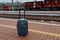 A dark blue suitcase on wheels stands on a train departure platform, a background of reflections,