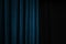 Dark blue velvet curtain on one side of a black theatre stage, event background concept with large copy space