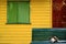 Dark blue wooden bench with a Calico cat in front of colorful house outer wall