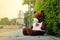 Dark brown bear doll sitting on the footpath sidewalk beside the road in lonely mood