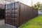 Dark brown cargo container stands near green grass