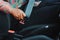 Dark brown skin African woman hand buckling safety belt in the car for automobile accident safety concept