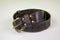 Dark brown stitched leather belt with yellow buckle and rivets on a white background