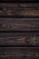 Dark brown wooden background. Four horizontal boards with knots. Natural wood texture. Vertical layout