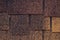 Dark brown and yellow surface of roofing tiles. Cover of shape of squares. Dark roof tile, grunge texture. Brick wall background.