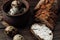 Dark buckwheat bread is spread with cottage cheese with herbs in a cut on a wooden table near quail eggs in a clay plate in a