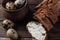 Dark buckwheat bread is spread with cottage cheese with herbs in a cut on a wooden table near quail eggs in a clay plate in a