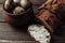 Dark buckwheat bread is spread with cottage cheese with herbs in a cut on a wooden table near quail eggs in a clay plate in a