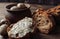 Dark buckwheat bread is spread with cottage cheese with herbs in a cut on a wooden table near quail eggs in a clay plate in a