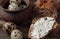 Dark buckwheat bread is spread with cottage cheese with herbs in a cut on a wooden table near quail eggs in a clay plate in a