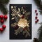 Dark card with handmade gold leaf flower and sprigs of conifers around red rowan ornament. Christmas card as a symbol of