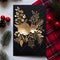 Dark card with handmade gold leaf flower and sprigs of conifers around red rowan ornament. Christmas card as a symbol of