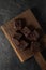 Dark chocolate brownies with choco drops on oak wood cutboard on dark background