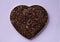 Dark chocolate in the shape of a heart on a neutral background top view