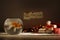 The dark Christmas composition consisting of golden fish in the circular aquarium at the blurred background of gifts