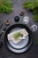 Dark christmas table setting design. Black plates, champagne glasses, fork and knife set with napkin, fir branch