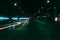 Dark city street at night with light trail from speeding car