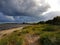 Dark clouds filled with rain meet the sunshine that lights up the sandy beach in Halmstad, Sweden.