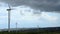 Dark clouds in stormy sky over wind farm, turbine blades rotate, weather change