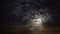 Dark clouds are transforming and moving across the night sky and moon. Time-lapse