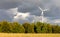 Dark clouds will bring rain. The wind turbine is still illuminated by the sun.