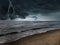 Dark cloudy sky with lightnings over beach and sea. Thunderstorm