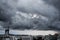 Dark cloudy storm on sky over the sea, with buildings in the city