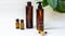 Dark cosmetic bottles and green natural leaves on a light background. Copy space Beauty salon blogger, salon therapy, minimalist