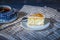 On a dark countertop, on a light checkered linen napkin, a white and blue patterned tea pair with tea and saucer with a piece of