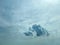 Dark cumulonimbus cloud amongst cirrus clouds in gray/blue sky.
