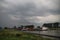 Dark Cumulonimbus clouds above sluice Julianasluis with cargoships on river Hollandsche IJssel in Gouda