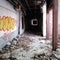 Dark, decaying hallway and graffiti covered walls of an abandoned building.