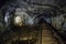 Dark dirty abandoned uranium mine with rusty remnants of railway, Bifurcation of tunnel