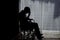 Dark emotion of handicapped Man sitting on wheelchair in front of a large panoramic window in hospital,He is sad and lonely