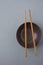 Dark Empty Bowl with Brown Bamboo Chopsticks on Grey Background. Japanese Chinese Asian Cuisine.