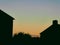 Dark evening with silhouettes of village houses, night city with sunset sky.