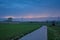 Dark evening sky over a street through the fields of the flemish countryside