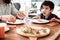 Dark-eyed beaming curly boy feeling happy eating pizza with father