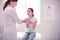 Dark-eyed little girl feeling calm while sitting in front of family physician