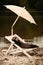 Dark ferret enjoying relaxation on beach chair with umbrella