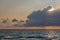 Dark fluffy cumulus clouds stormy sky above a blue surface of sea at sunset