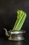 Dark food background with old metal kettle and fresh celery.