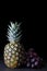 Dark Food - single pineapple fruit with dark black red grapes