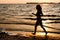 Dark glowing silhouette of woman running along beach